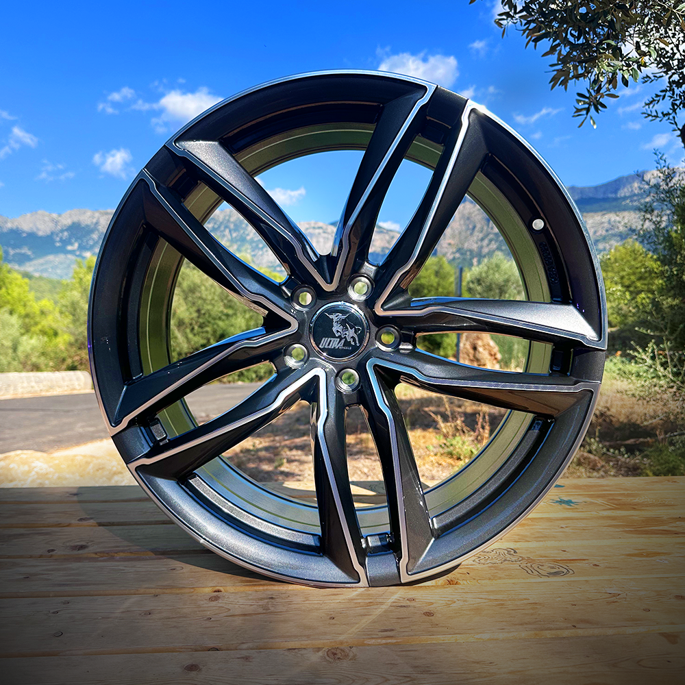 Close-up of a stylish black alloy wheel set against a scenic outdoor backdrop.
