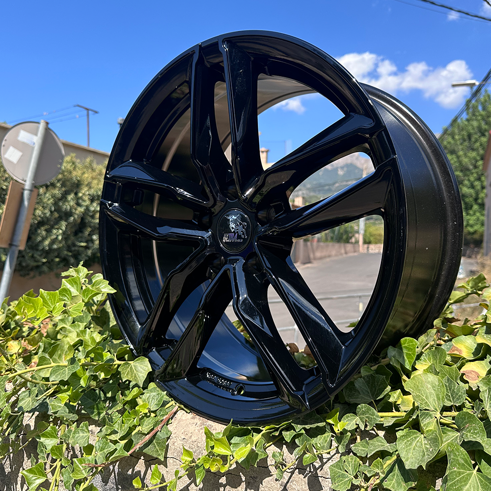 A black alloy wheel resting on a bed of greenery.